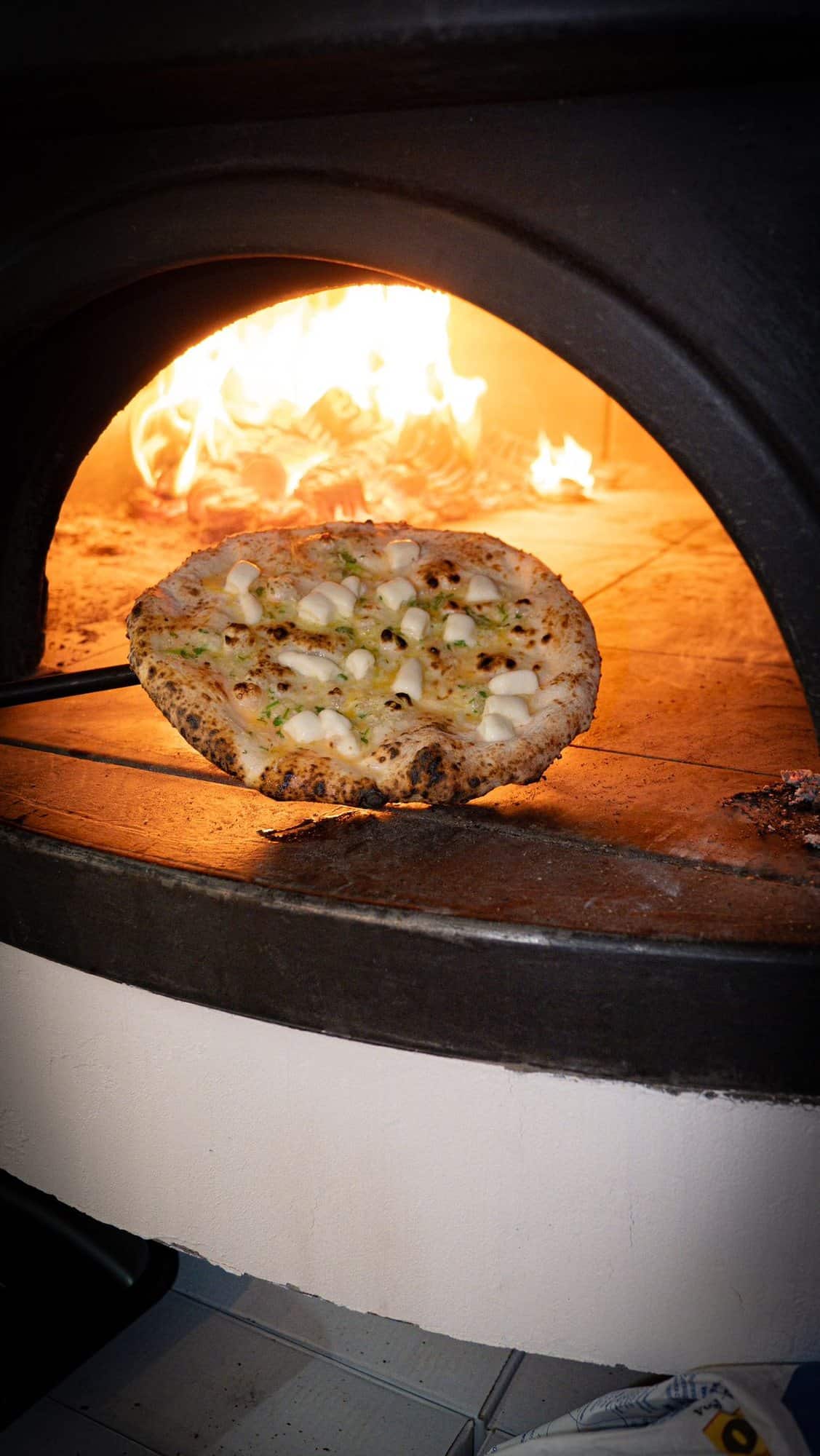 A Neapolitan pizza on the peel against the flame of the wood-fired oven at Lacco